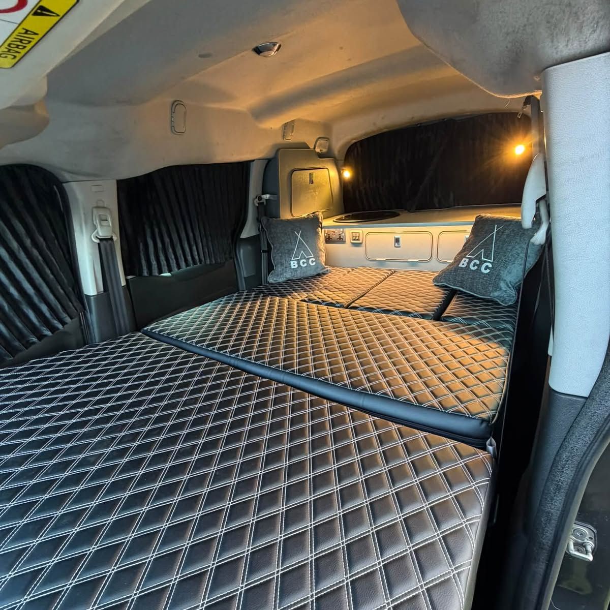 Diamond-quilted bed made up in the back of a van, with Boot Camp Campers cushions.