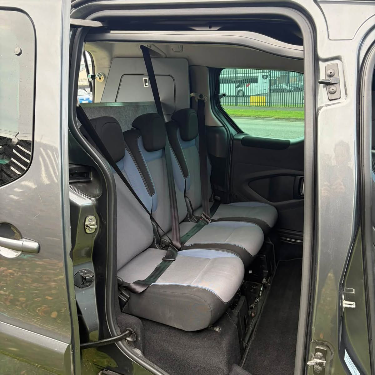 Two rows of seats seen through an open sliding door, with a quilted panel behind them.